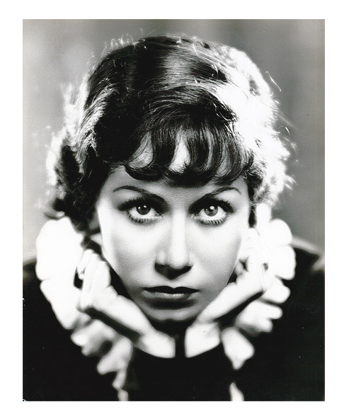 Portrait photograph of a young woman resting her chin in her hands and looking directly at the viewer.