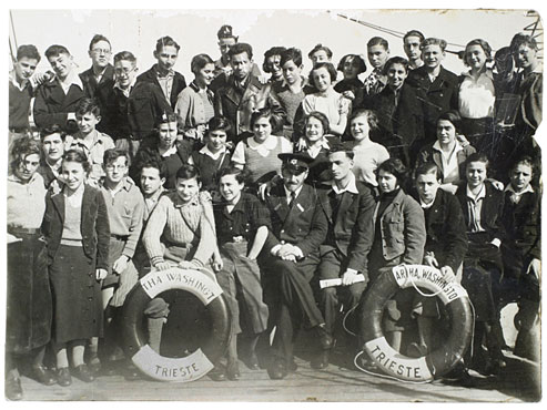 Group photo of around forty boys and girls looking cheerfully at the camera. The two life rings in front bear the names of the ship, "Martha Washington," and its home port, Trieste.