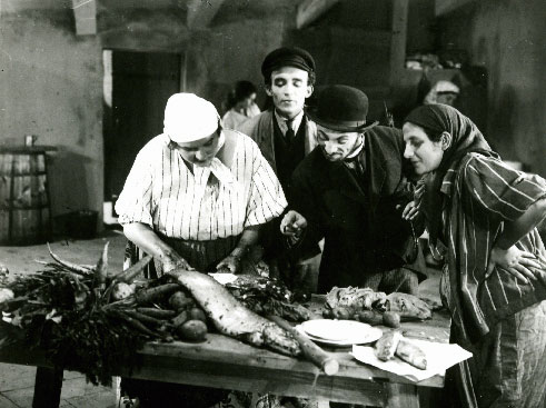 Film still of several people standing around a market stall looking at a fish