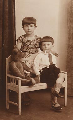 Mädchen und Junge mit Teddybär auf einer kleinen Bank