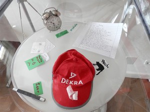 An ink eraser, a baseball cap, and an alarm clock in a showcase