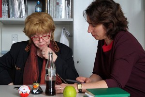 Two women on a table looking on a paper