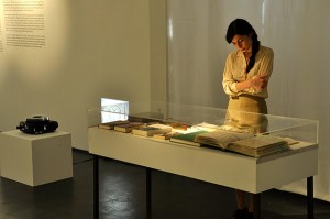 A woman standing in front of a showcase with books.