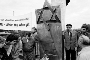 Demonstrators in front of a memorial with the Magen David and a poster with the words "Ausländerfeindlichkeit" (xenophobia) and "We need more courage."