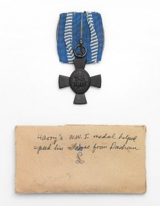 An Order of Merit in form of a cross and an envelope with the note "Harry's WWI medal helped speed his release from Dachau"