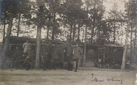 black and white photograph of several uniformed soldiers in front of a cabin in the woods