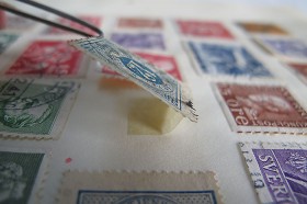 stamp album with tweezers holding one single stamp