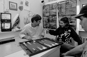 Black and white photography: a man with kippa is playing Backgammon with two kids