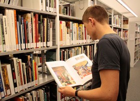 Man with a book in front of a bookshelf