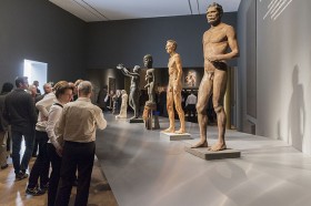 Visitors in the exhibition room in front of different naked and male sculptures