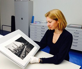 color photograph of a woman holding the photograph of Ilse Bing