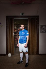 Young man in a room in front of a a bar with a football