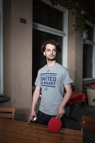 Young man with table tennis racket and ball outside at a table