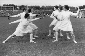 Black-and-white photo: six women fencers at a sporting event