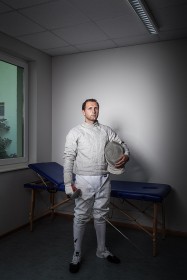 Young man with floret and helmet in fencing suit