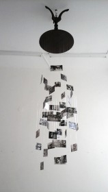 A black table hanging from a white ceiling, with painted glass plates hanging down from the table