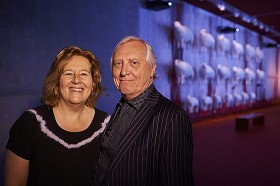 Portrait of a couple in an exhibition room, in the background sculptures of white sheep