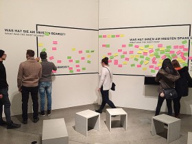 Six visitors stand in front of a wall with sticky notes in different colours