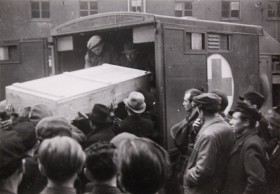 Black and white photograph of a coffin transported into a car