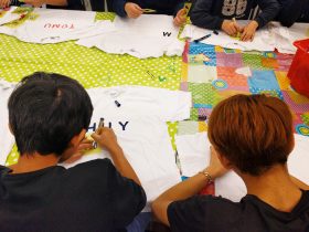 Two boys writing their names on T-shirts