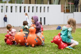 In the museum garden, four children ride the rubber animal mentioned in the text