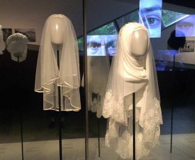 two white head coverings for women displayed in the exhibition