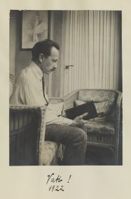 Black-and-white photo of Ludwig Scherk sitting in the living room, reading.