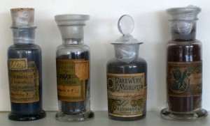 Vier Glasfläschchen mit Glasstöpseln und alten Etiketten