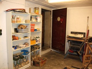 Regale mit Werkzeugen, Farben und weiteren Gegenständen neben einer geöffneten Tür