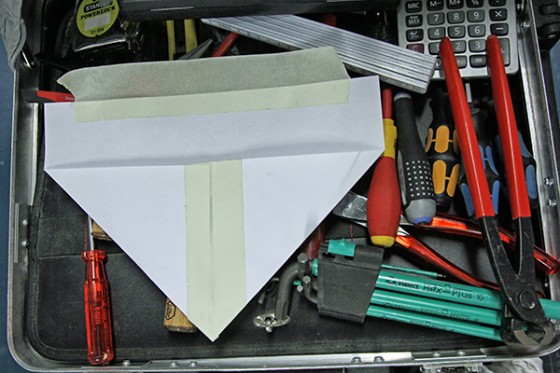 Werkzeugkasten auf dem eine gefaltete und verklebte Papiertüte liegt