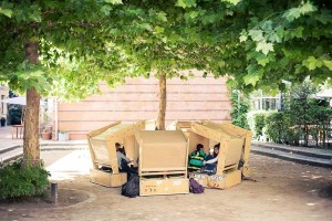 Holzhütten in einem Kreis auf dem Schulhof, die Schüler sitzen darin