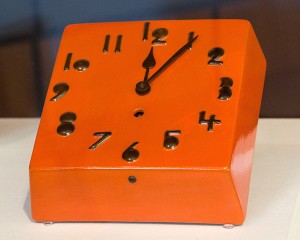 Orange glasierte, quadratische Uhr mit schwarzen Ziffern