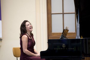 Eine lachende Frau sitzt an einem Konzertflügel