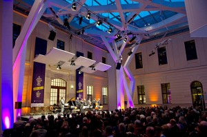 Musicians on the stage in a glass-covered courtyard in front of an audience