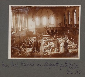 schwarz-weiß Fotografie eines Krankensaals mit mehreren Personen eingerichtet in einer Kirchenkapelle