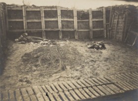 schwarz-weiß Fotografie mit Blick in einen Schützengraben mit einem totem Soldaten liegend