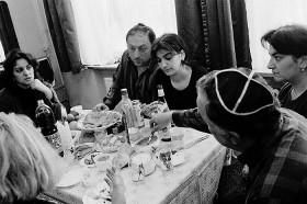 Eine Familie sitzt um einen reichlich gedeckten Tisch und isst
