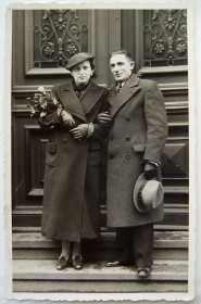 Schwarz-Weiß-Fotografie eines Paares auf einer Treppe, sie hat einen Blumenstrauß in der Hand
