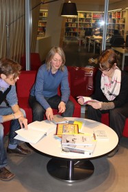 Drei Frauen sitzen um einen Tisch und halten Bücher in den Händen