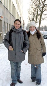 Farbfotografie eines jungen Paares in Winterkleidung auf einer schneebedeckten Straße spazierend