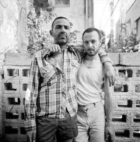 Schwarz-weiß Fotografie von zwei Männern, die Arm in Arm nebeneinander stehen