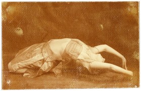 Junge Frau in Tanzpose auf dem Rücken liegend
