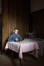 Junger Mann sitzt an einem Tisch mit Schachspiel