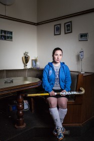 Eine junge Frau sitzt an einem Tisch mit einem Hockeyschläger in der Hand
