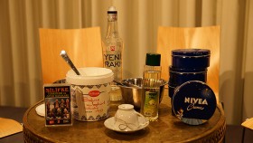 Ein Tisch mit verschiedenen Objekten darauf: Nivea-Creme, Sahne-Jogurt, eine Mokkatasse, Raki.