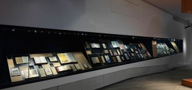 Eine lange Vitrine mit vielen Büchern und Zeitschriften, Coverbildern und Begleittexten