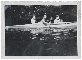 Schwarz-weiß Fotografie von einem Mann, zwei Frauen und einem Mädchen in einem Kayak