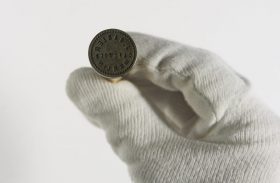 Detailaufnahme einer Hand in weißem Handschuh, die ein Siegel hält
