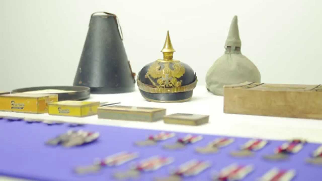 Military headgear and other historical objects on a table.