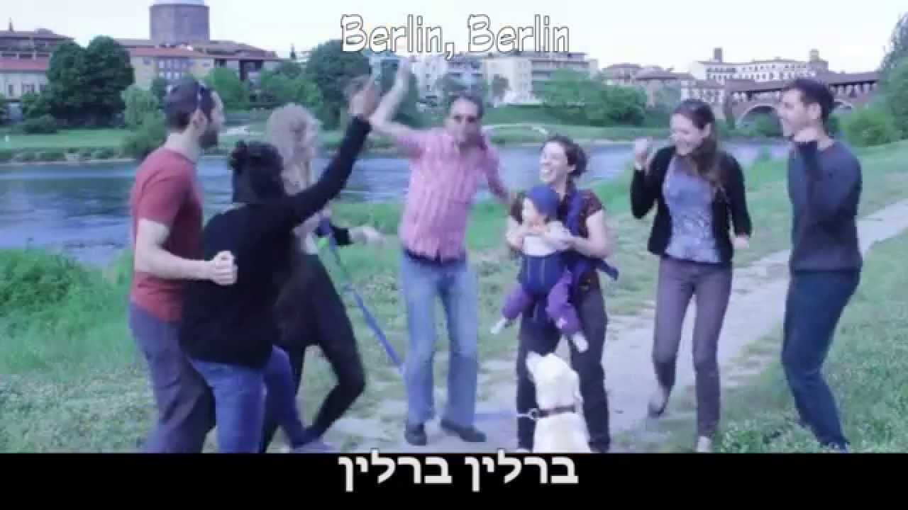 A group of young adults with a baby and a dog dance on a riverbank.